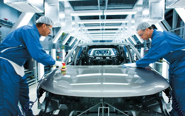 Two workers stand beside a vehicle in a production center