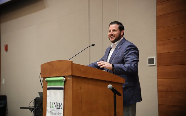 Andrew Carnes speaking at podium during Good News Gathering