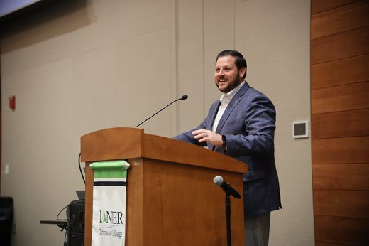 Andrew Carnes speaking at podium during Good News Gathering