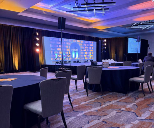 Fall Forum Auditorium with stage, spotlight, tables, and chairs