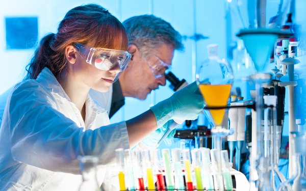 Female and Male Scientists working in a laboratory with different color chemicals