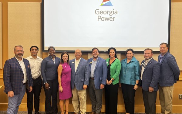 Group of economic development professionals stand together below the Georgia Power logo on a screen