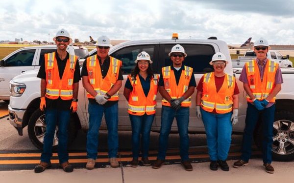 group of construction workers in oranage safety vests stand in front of a truck