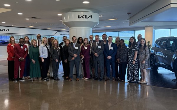 A group of educators stand together in front of a KIA sign for the GA Superintendents Academy
