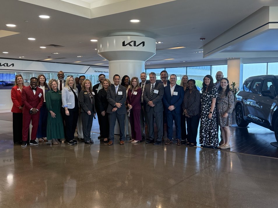 A group of educators stand together in front of a KIA sign for the GA Superintendents Academy